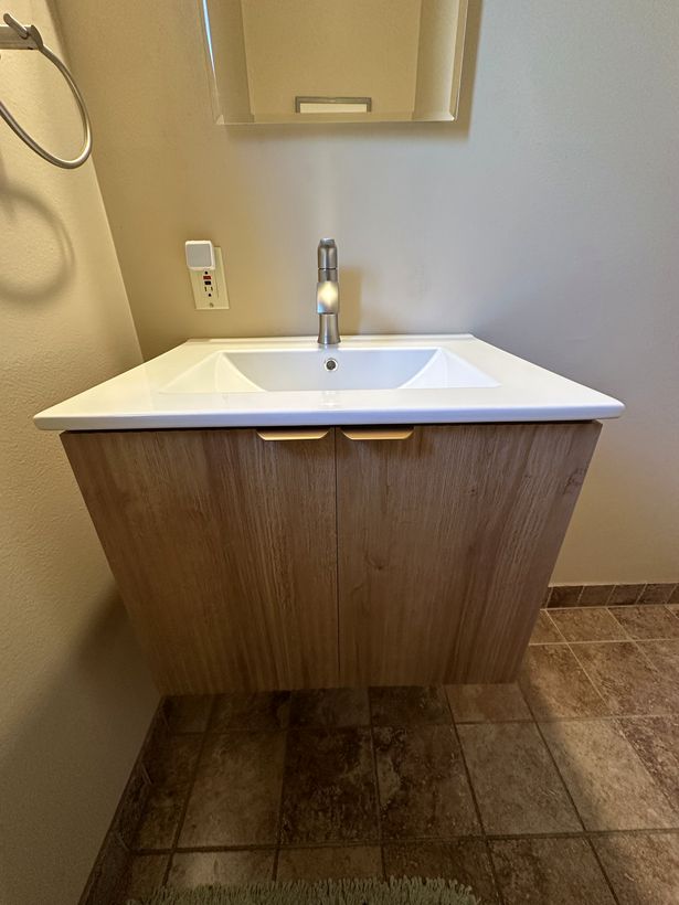Wall-hung wood-grain vanity with white ceramic top and brushed nickel faucet